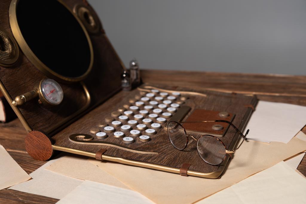 Steampunk laptop, glazen en documenten op houten tafel geïsoleerd op grijs - Foto, afbeelding