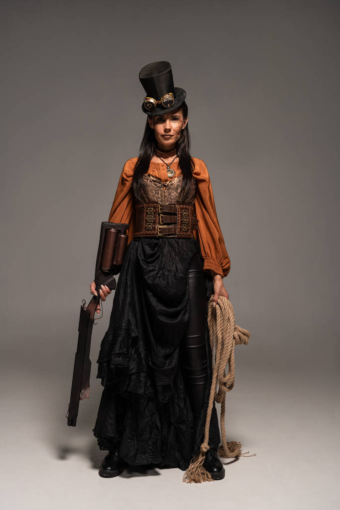 full length view of attractive steampunk woman holding guy and lasso on grey - Photo, Image