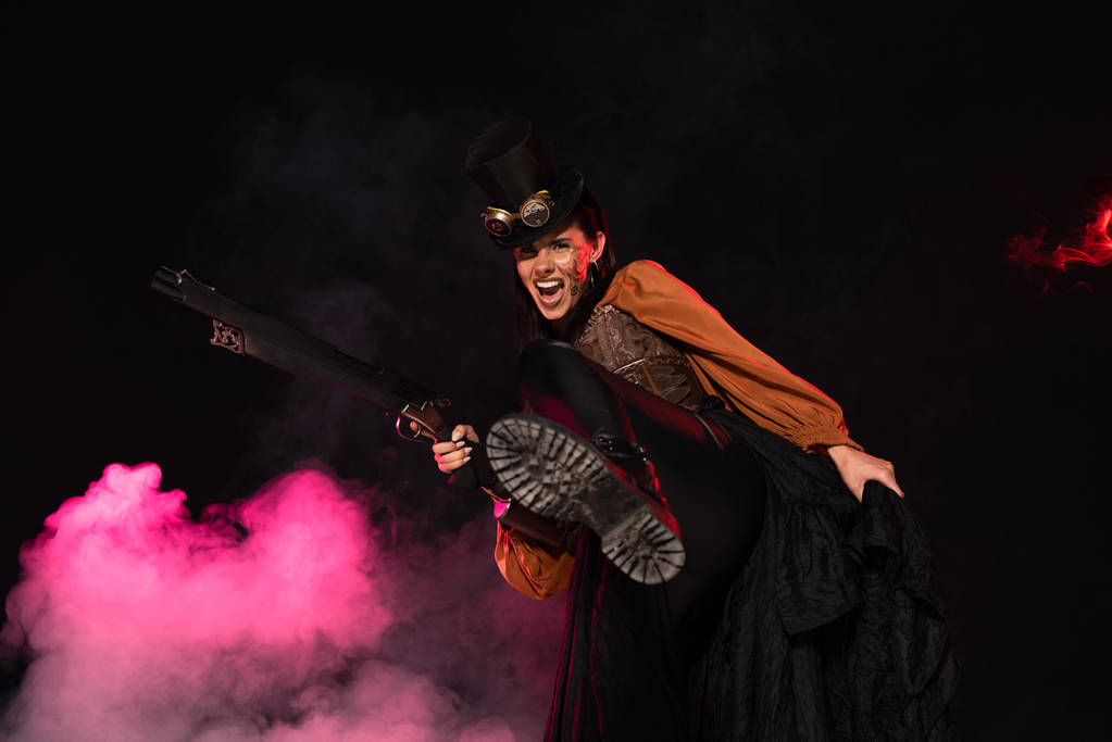 aggressive steampunk woman in top hat holding gun in pink smoke on black - Photo, Image