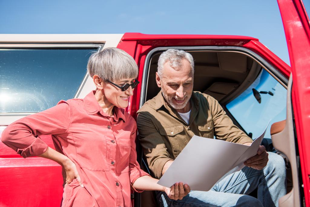voyageur âgé souriant assis en voiture rouge et regardant la carte avec sa femme
 - Photo, image