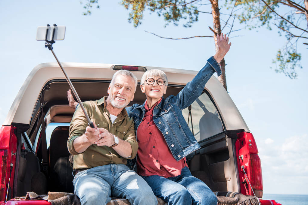 mosolygó Senior pár ül a kocsiban, és figyelembe selfie - Fotó, kép