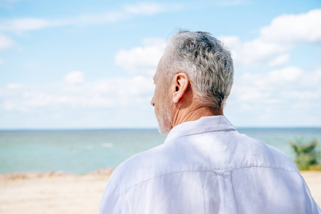Widok z tyłu starszy człowiek w białej koszuli na plaży w słoneczny dzień - Zdjęcie, obraz