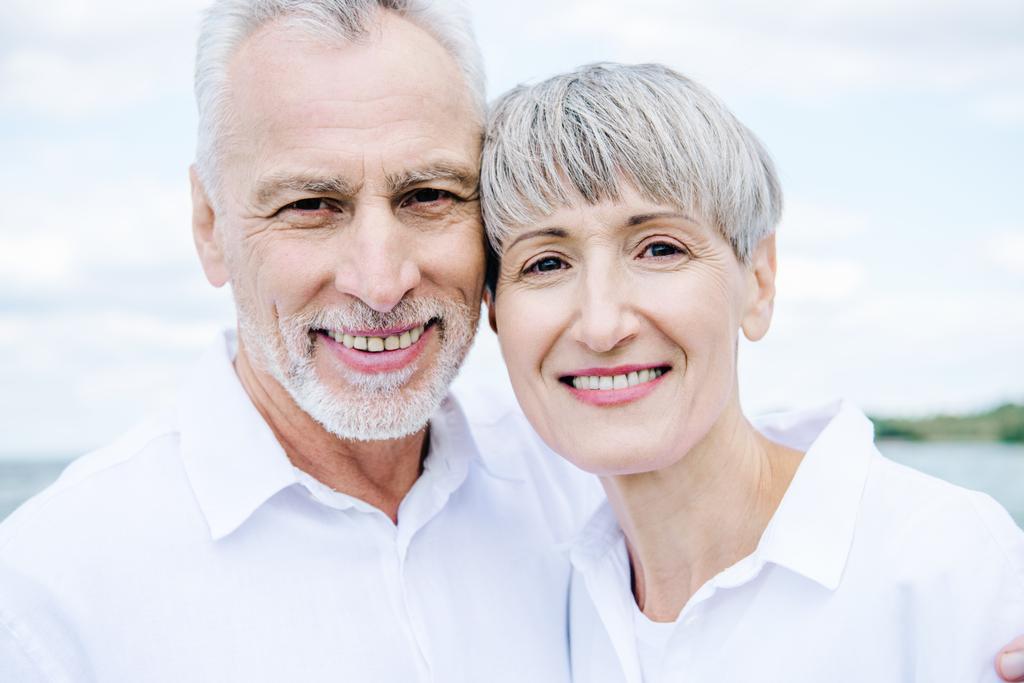 vista frontale di sorridere felice coppia anziana in camicie bianche guardando la fotocamera
 - Foto, immagini
