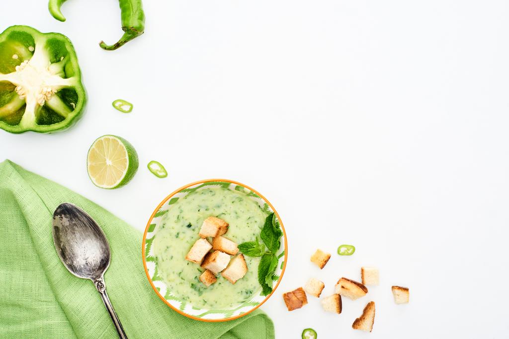 白に分離ナプキンとスプーンを添えたおいしいクリーミーな緑色の野菜スープのトップビュー - 写真・画像