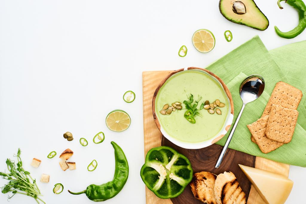 вид зверху смачний вершково-зелений овочевий суп, поданий з грінками, відповідає крекерам ізольовано на білому
 - Фото, зображення