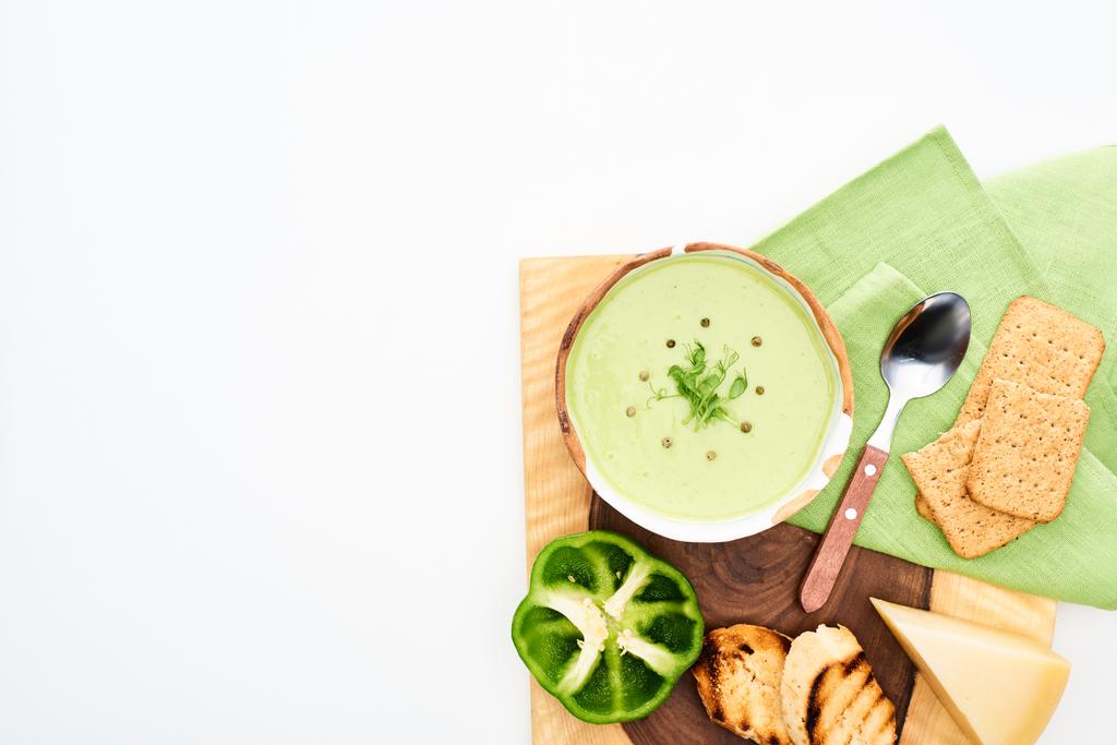 おいしいクリーミーな緑の野菜スープのトップビューは、白に分離クルトンとチーズと木製のまな板上で提供 - 写真・画像