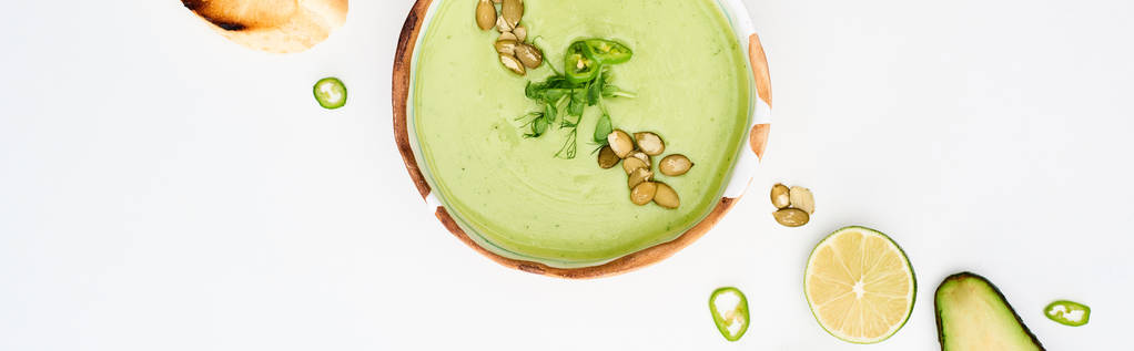 panoramic shot of delicious creamy green vegetable soup near lime and jalapenos isolated on white - Photo, Image