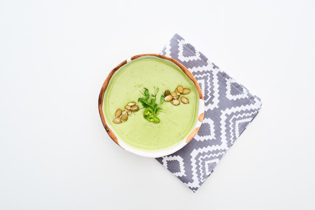 vista superior de la deliciosa sopa de verduras verde cremosa con brotes y semillas de calabaza en la servilleta aislada en blanco
 - Foto, imagen