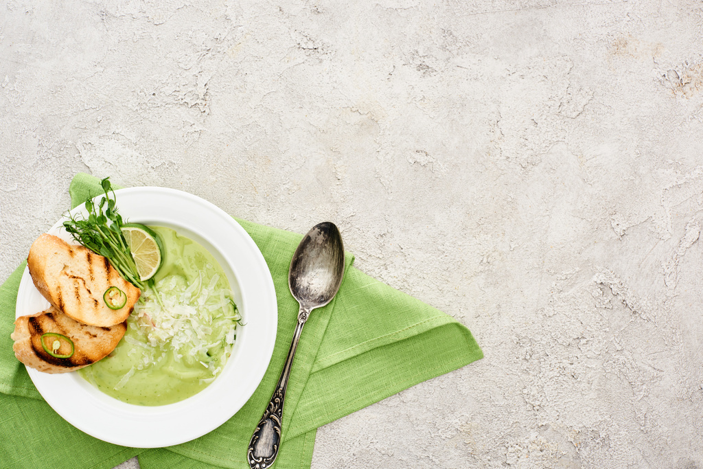 kaşık ve yeşil peçete ile servis kruton ile lezzetli kremsi yeşil sebze çorbası üst görünümü - Fotoğraf, Görsel