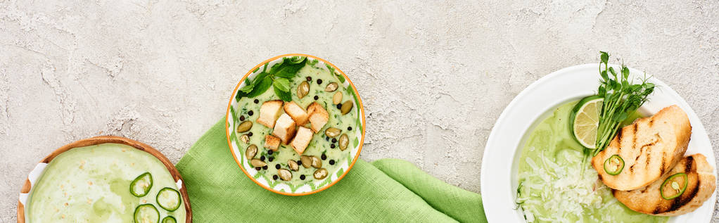 緑のナプキンにクルトンを添えたおいしいクリーミーなグリーンスープのパノラマショット - 写真・画像