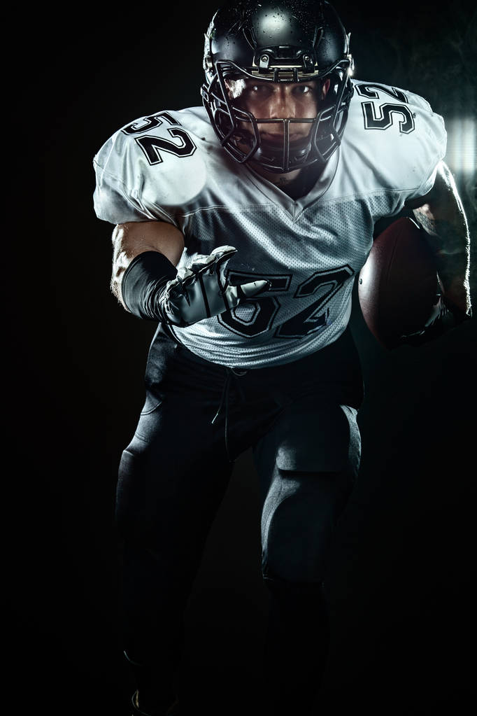 煙と黒い背景にヘルメットのアメリカンフットボールのスポーツマン選手。スポーツとモチベーションの壁紙. - 写真・画像