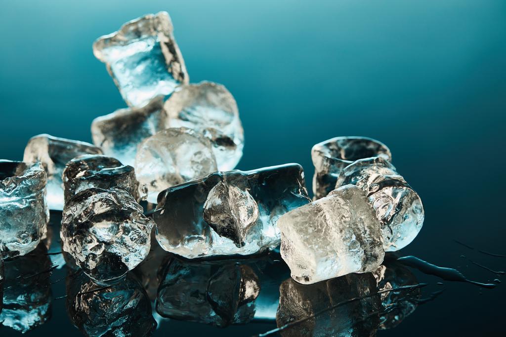 stos przezroczystego topniejącego kostki lodu na Szmaragdowym tle - Zdjęcie, obraz