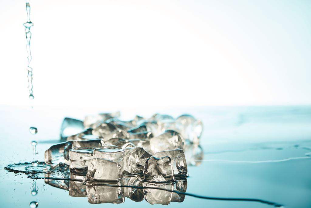montão de cubos de gelo fundidos transparentes com poças de água e gotas sobre fundo esmeralda e branco
 - Foto, Imagem