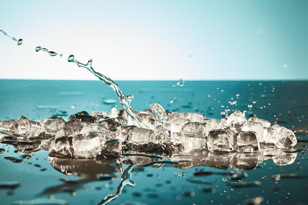 エメラルドと白の背景に透明な溶融氷キューブと水のスプラッシュ - 写真・画像