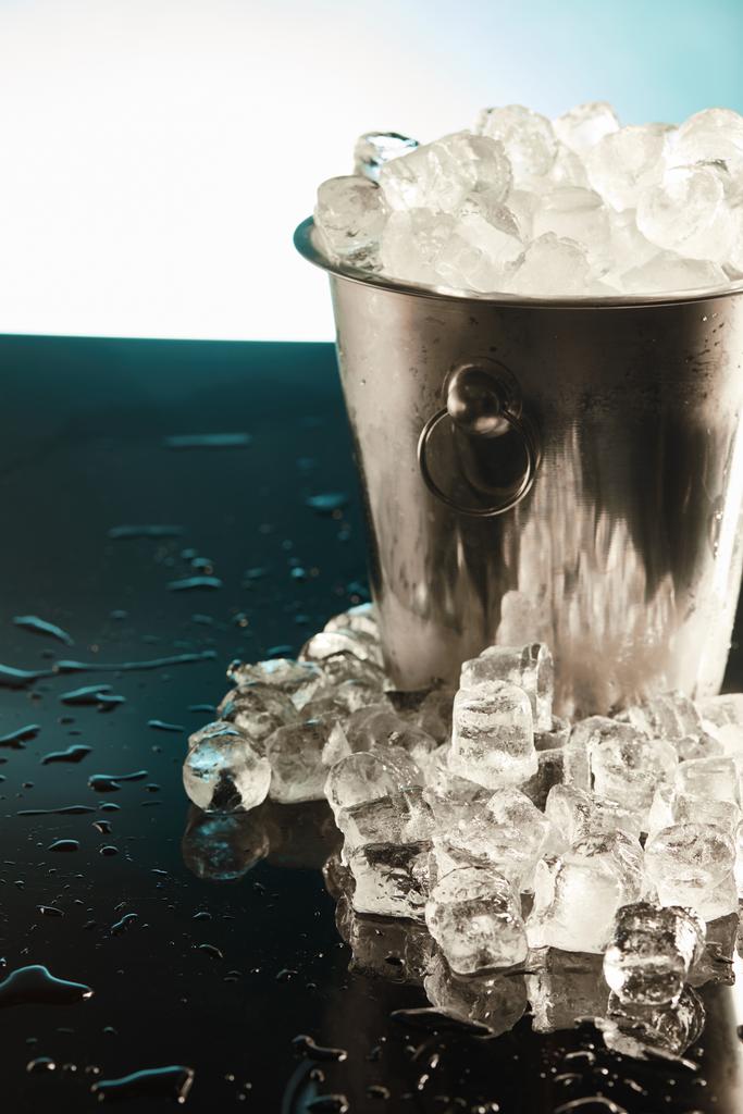 прозрачные кубики льда в металлическом ведре на изумрудной поверхности
 - Фото, изображение