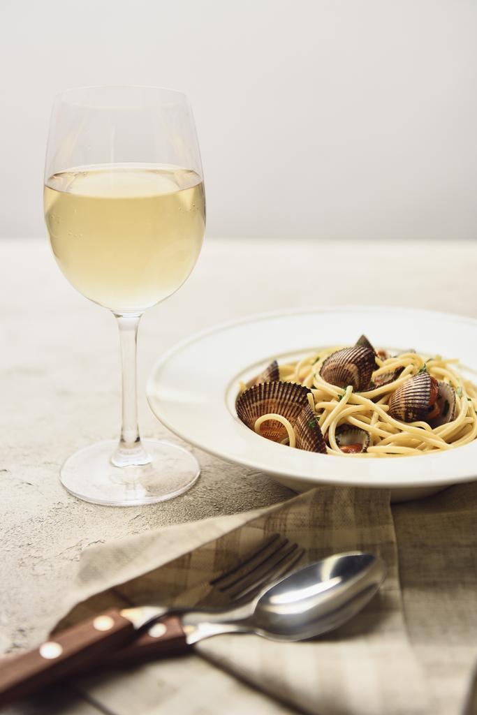 νόστιμα ιταλικά ζυμαρικά με θαλασσινά που σερβίρονται με λευκό κρασί που απομονώνεται σε γκρι - Φωτογραφία, εικόνα