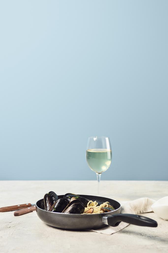 вкусная итальянская макароны с морепродуктами подается в сковороде с белым вином изолированы на синий
 - Фото, изображение