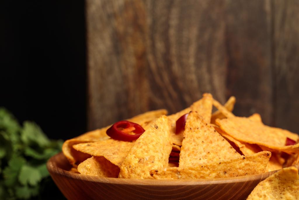 vista de cerca de nachos mexicanos con chiles cerca de tablas de cortar de madera aisladas en negro
 - Foto, Imagen