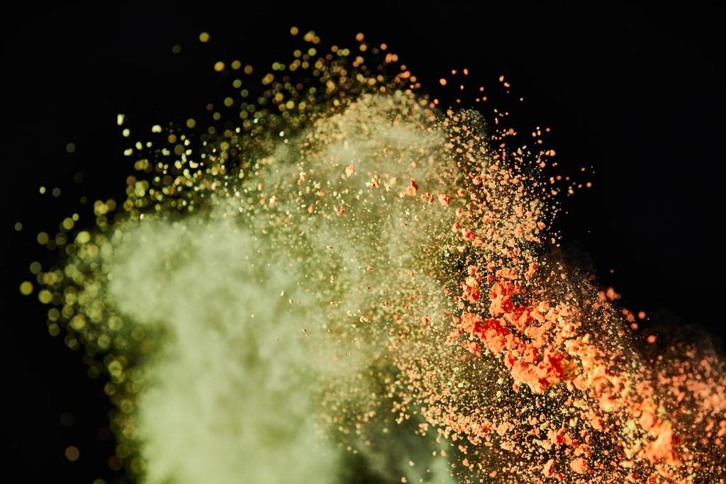 cepillo cosmético con colorido polvo amarillo y naranja explosión sobre fondo negro
 - Foto, Imagen