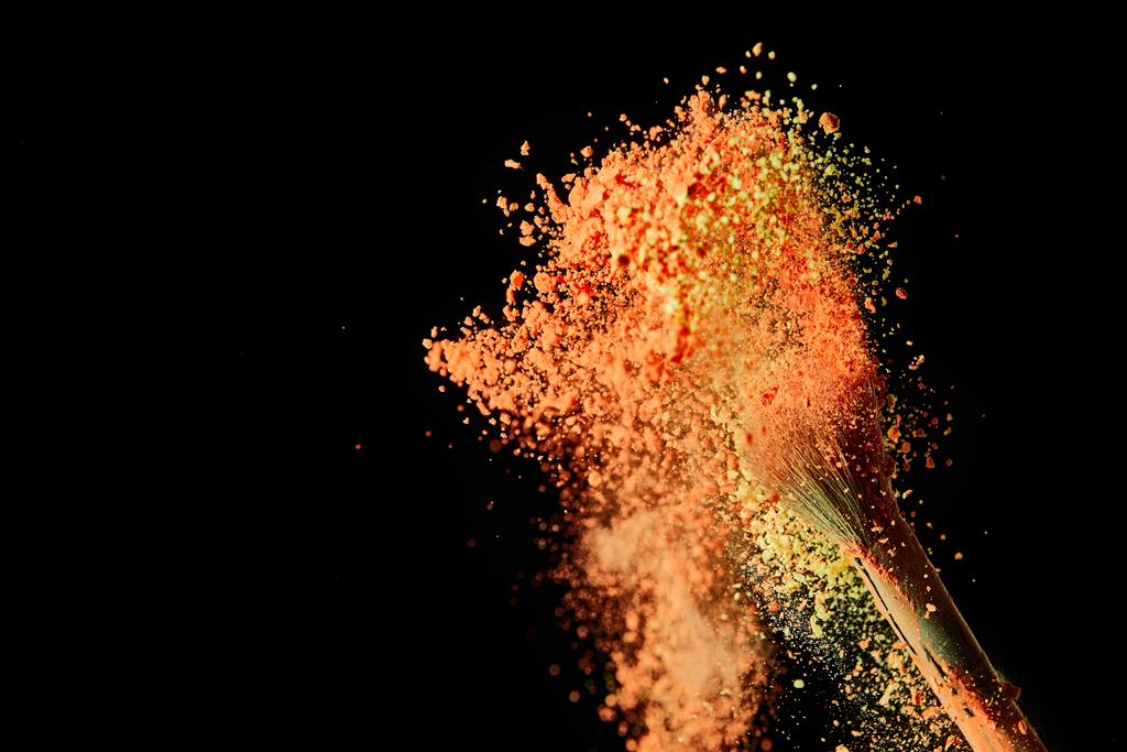 escova cosmética com explosão de tinta laranja no fundo preto com espaço de cópia
 - Foto, Imagem