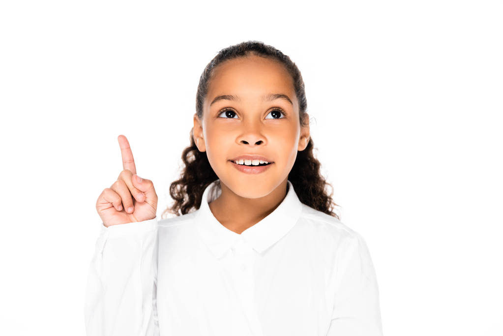 cheerful african american schoolgirl looking up and showing idea gesture isolated on white - Photo, Image