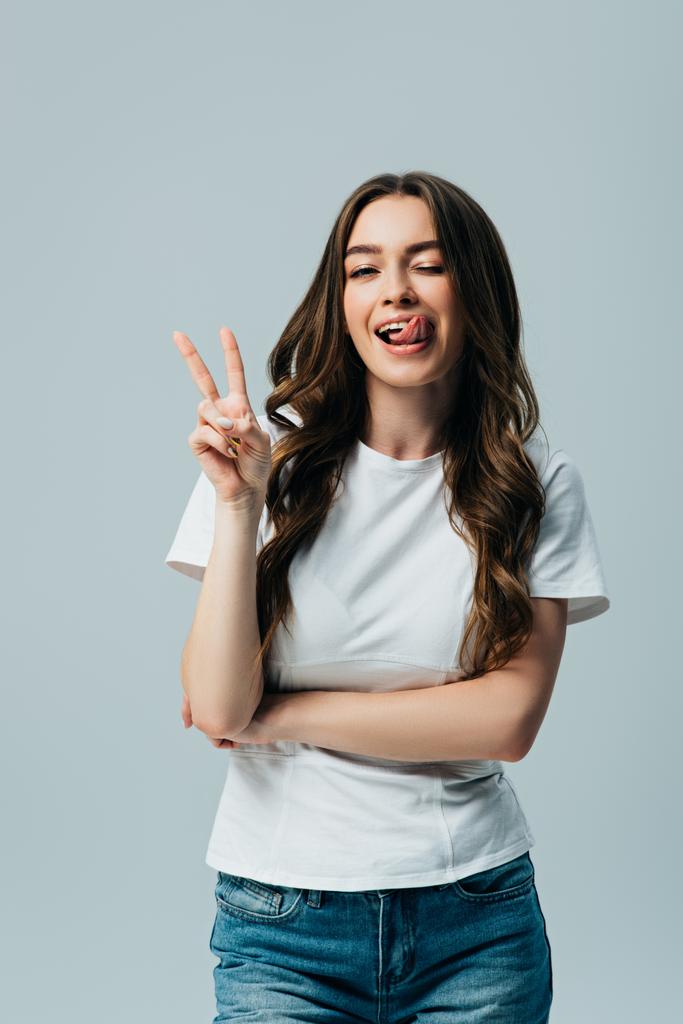 hermosa chica en camiseta blanca mostrando lengua y signo de paz aislado en gris
 - Foto, Imagen