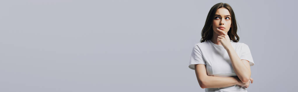 serieuze doordachte mooi meisje in wit t-shirt op zoek weg geïsoleerd op grijs, panoramisch schot - Foto, afbeelding