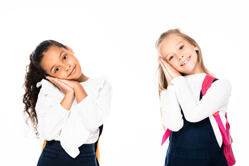 two smiling, tired multicultural schoolgirls looking at camera isolated on white - Photo, Image
