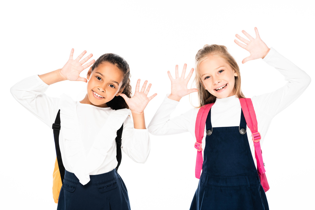 dvě usmívající se multikulturní školačky ukazující křídou potřísněné ruce izolované na bílé izolované na bílém - Fotografie, Obrázek