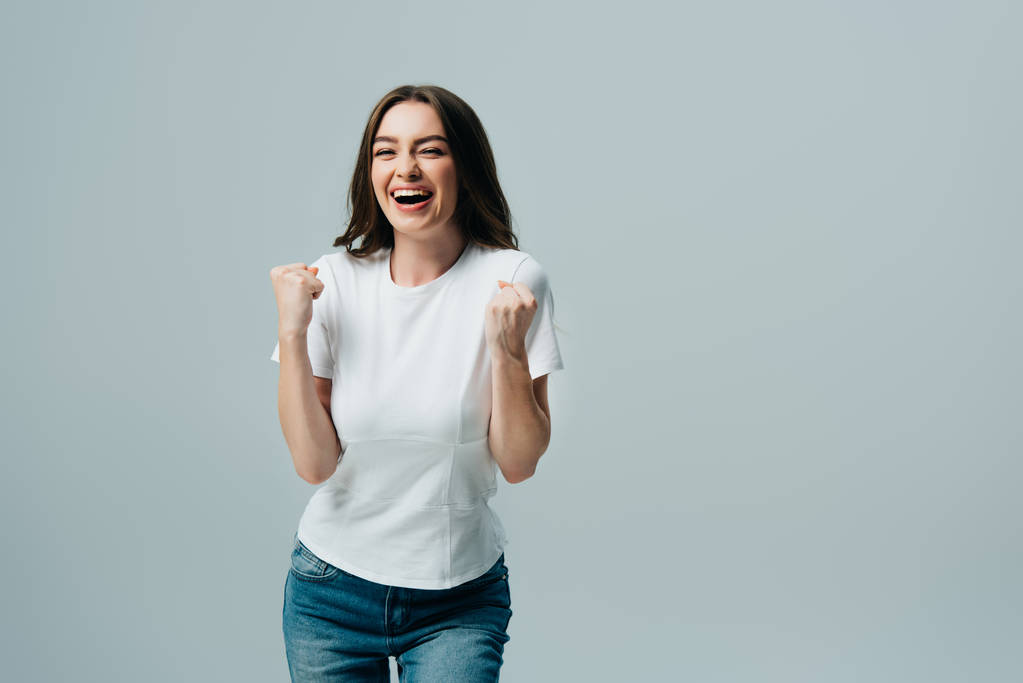 vzrušená šťastná dívka v bílém tričku ukazující Ano gesto izolované na šedé - Fotografie, Obrázek