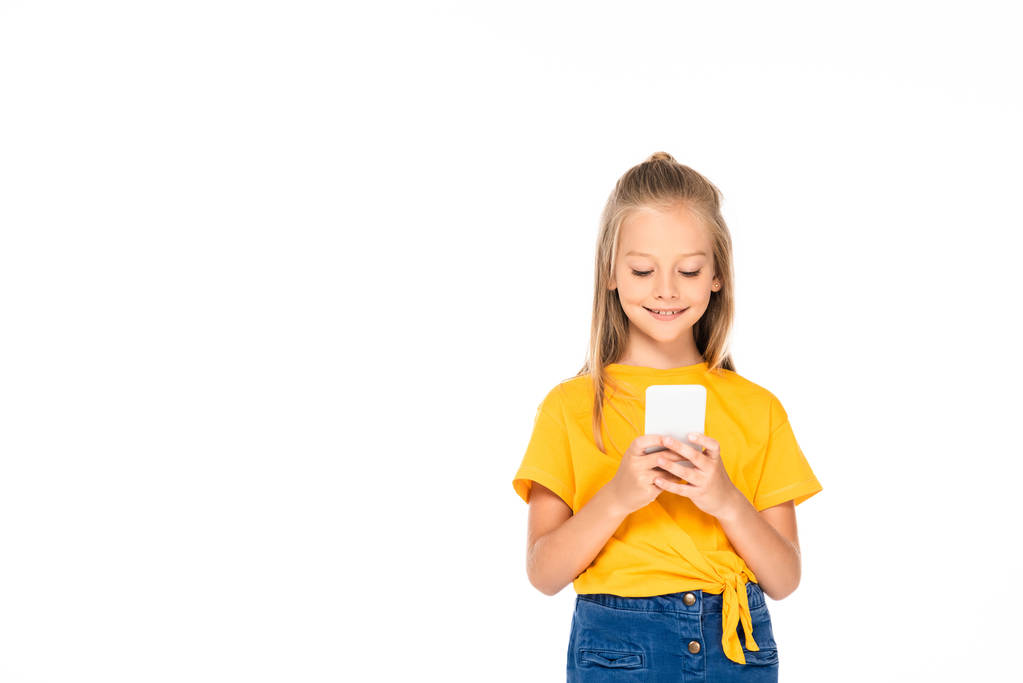 schattig Kid glimlachend tijdens het gebruik van een smartphone geïsoleerd op wit - Foto, afbeelding