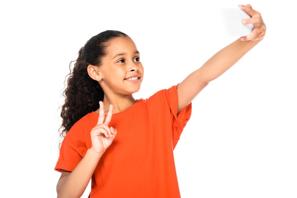 iloinen afrikkalainen amerikkalainen lapsi näyttää voittomerkkiä samalla kun selfie eristetään valkoisella
 - Valokuva, kuva