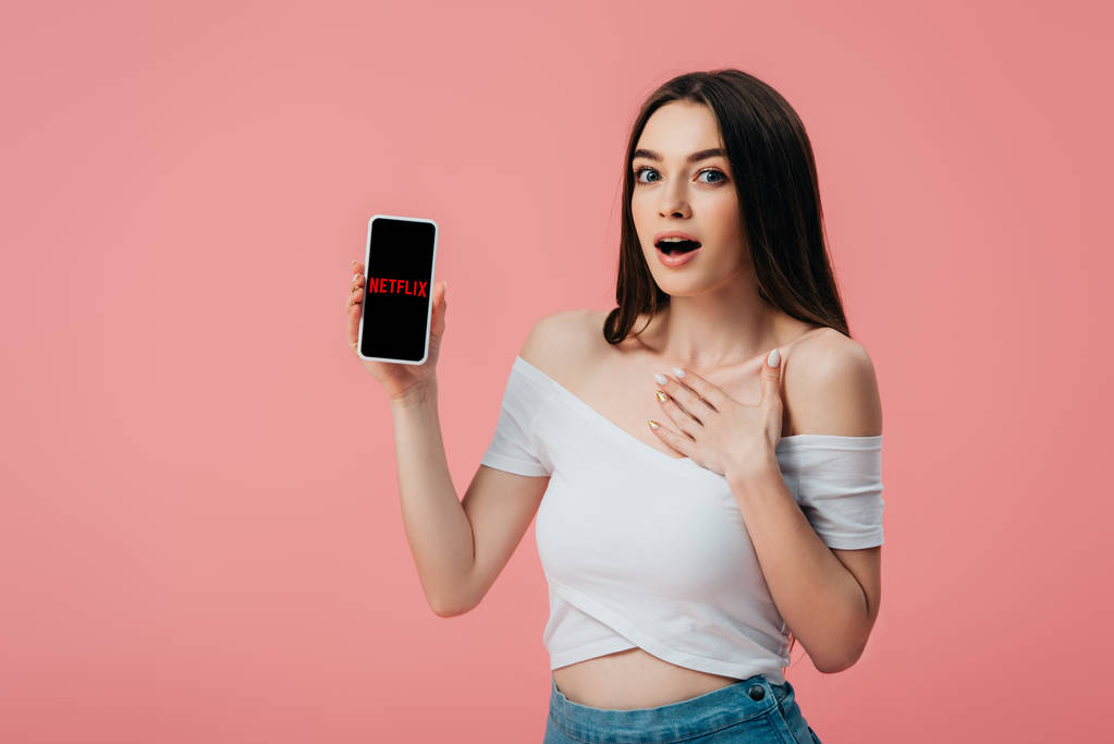 Kijów, Ukraina-6 czerwca 2019: piękna zszokowana dziewczyna trzyma smartfon z aplikacją Netflix na białym tle - Zdjęcie, obraz