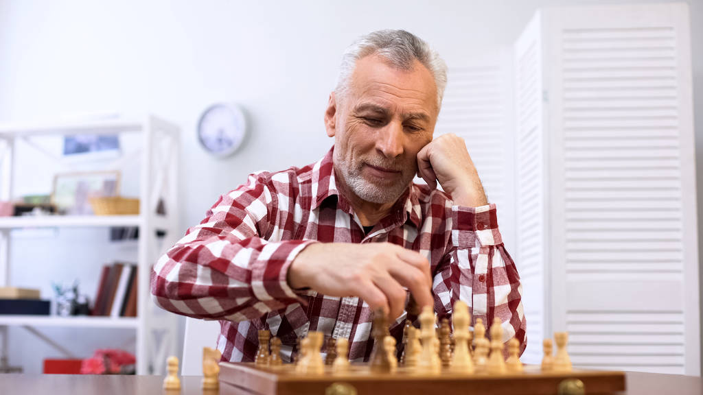 Szczęśliwy starszy człowiek gra w szachy sam, szkolenia dla konkurencji szachowej, mat - Zdjęcie, obraz