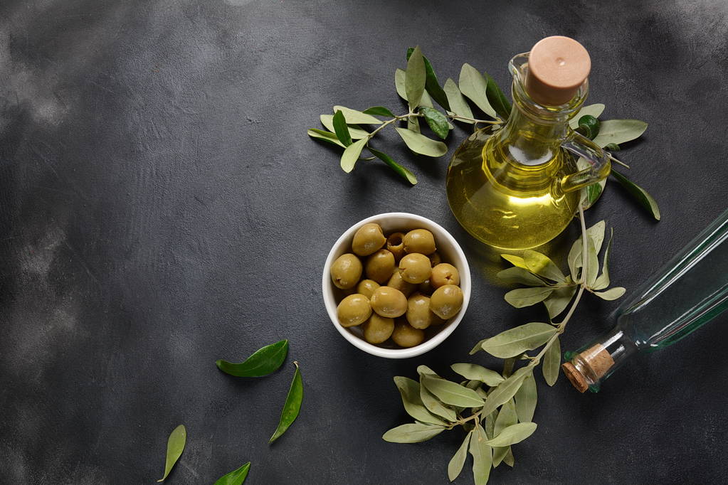 Olio extra vergine di oliva, ramoscello di ulivo e olive su fondo scuro
 - Foto, immagini