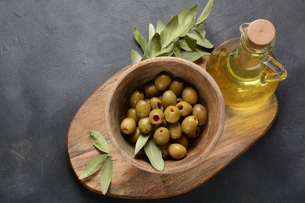Aceite de oliva virgen extra, rama de olivo y aceitunas sobre un fondo oscuro
 - Foto, imagen