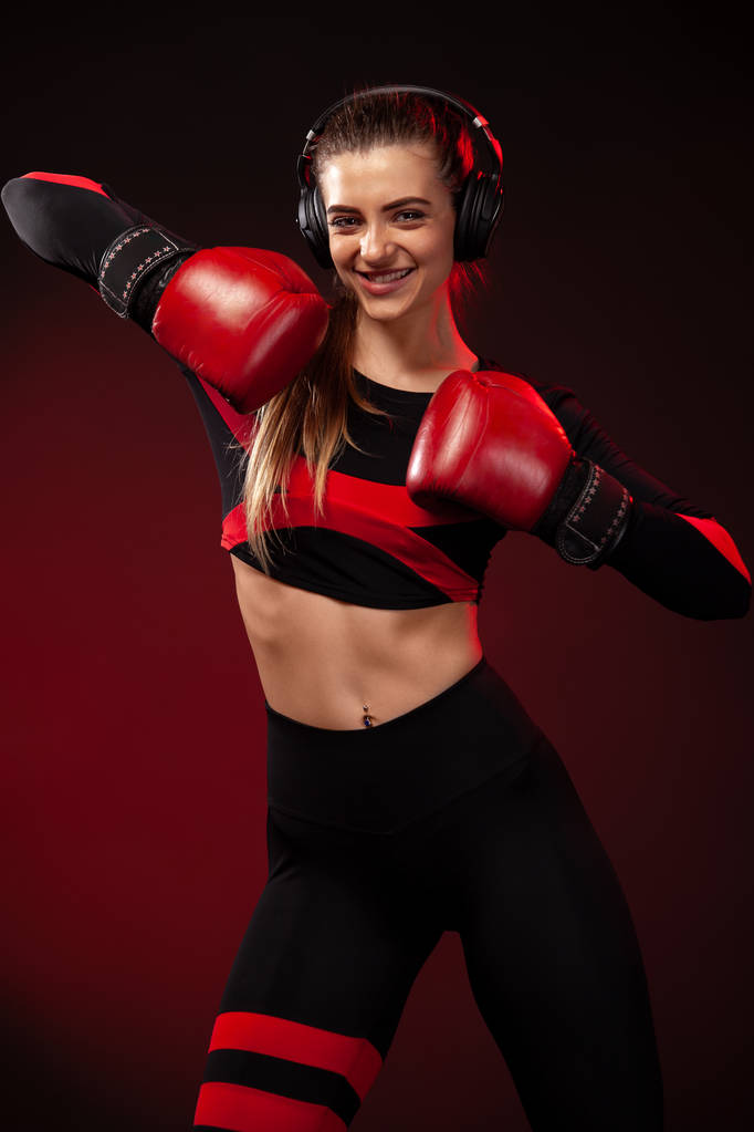 Feliz y sonriente joven boxeadora deportista en entrenamiento de boxeo. Chica usando guantes, ropa deportiva
. - Foto, imagen