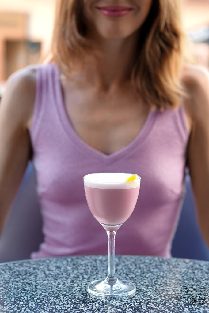 Fille méconnaissable derrière la table avec cocktail cerise brandy sur la terrasse extérieure (soft focus photo
) - Photo, image