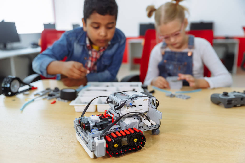 Gemengde rassengroep school kinderen zitten in de klas met DIY robot, stem onderwijsconcept. - Foto, afbeelding