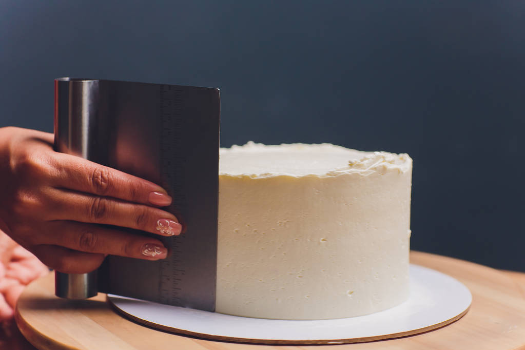 жіночі руки роблять бісквітний торт з білим кремом з використанням кулінарного шпателя
. - Фото, зображення