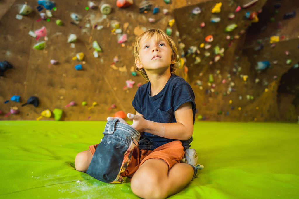 niño pequeño escalando una pared de roca con botas especiales. interior
 - Foto, Imagen