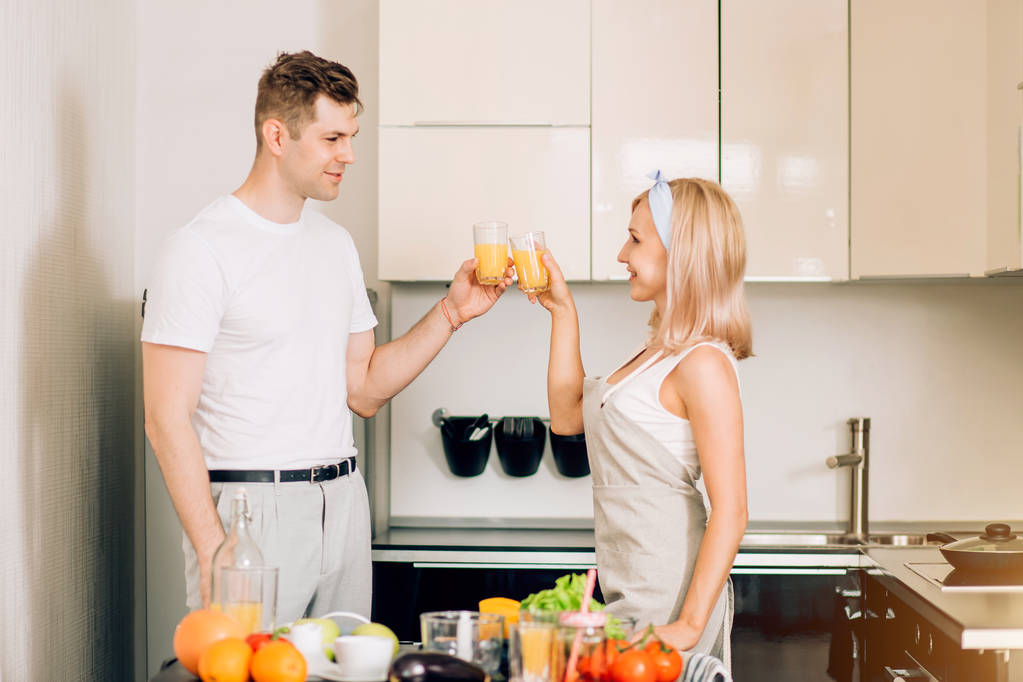 キッチンで一緒に新鮮な有機ジュースを作るカップル - 写真・画像