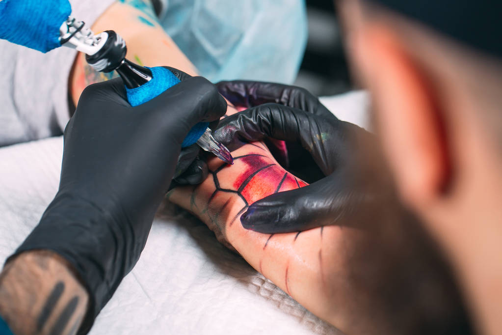 Profesjonalny tatuażysta robi tatuaż na ręce młodej dziewczyny. - Zdjęcie, obraz