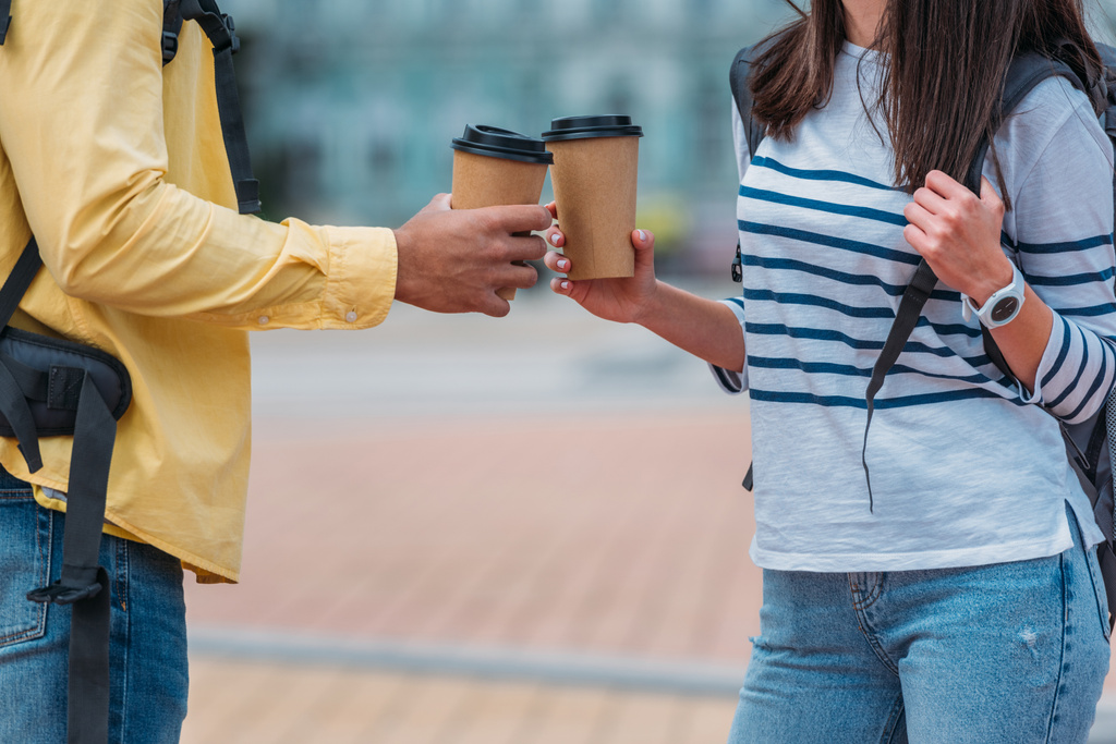 Levágott kilátás bi-arc férfi és a nő a hátizsák tartó papír csésze kávét az utcán  - Fotó, kép