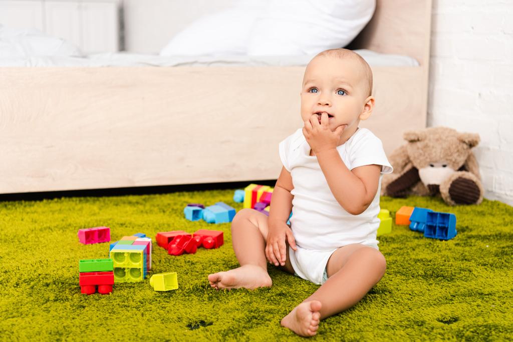 緑の床に囲まれたウートのおもちゃに座っているかわいい小さな子供 - 写真・画像