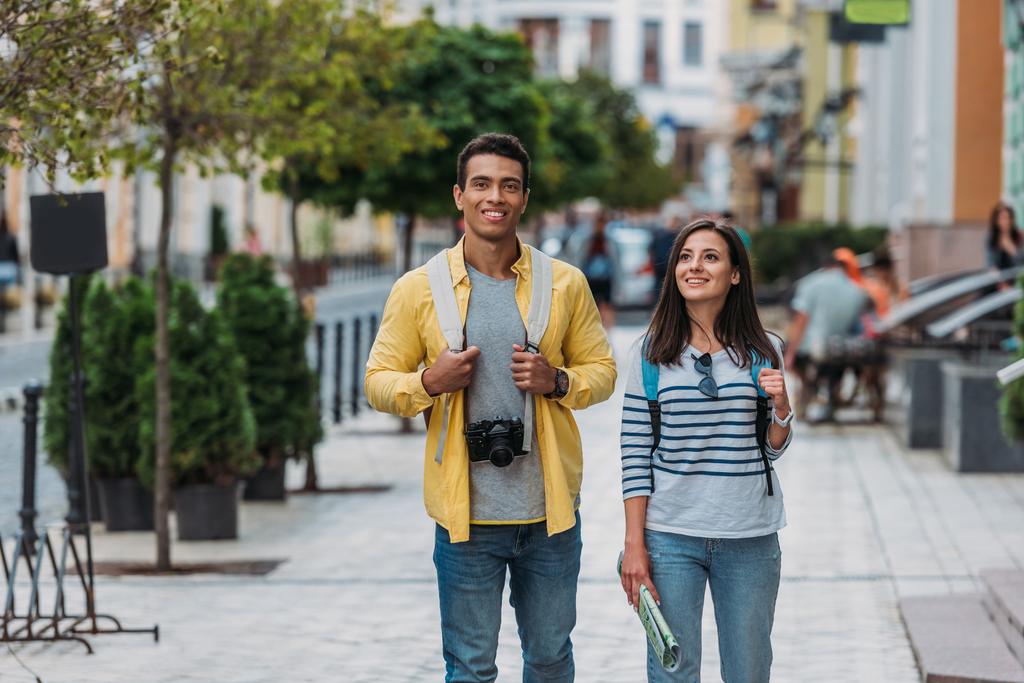 glückliche Frau geht mit gutaussehendem Mann auf Straße in der Nähe von Gebäuden  - Foto, Bild