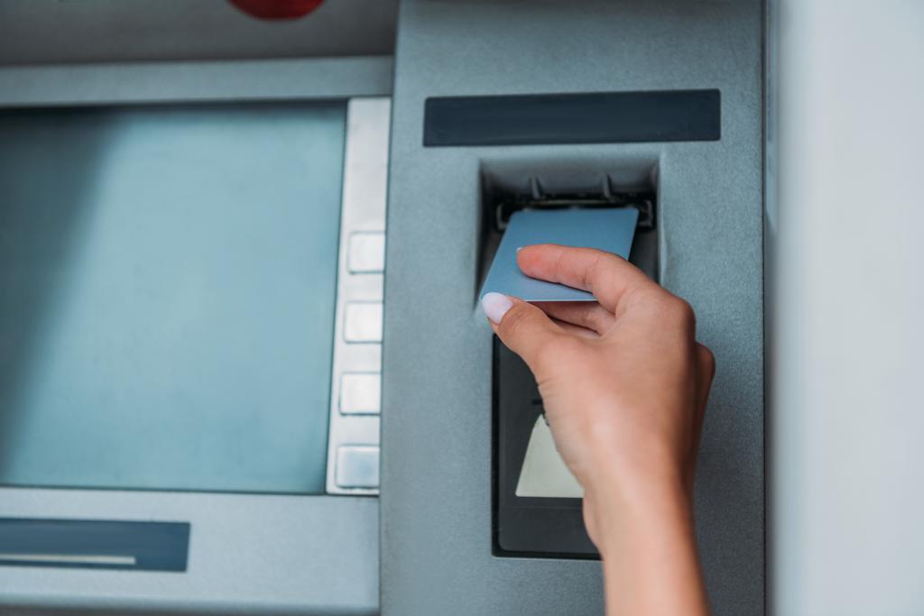 ATMマシンにクレジットカードを入れる女性のトリミングビュー  - 写真・画像