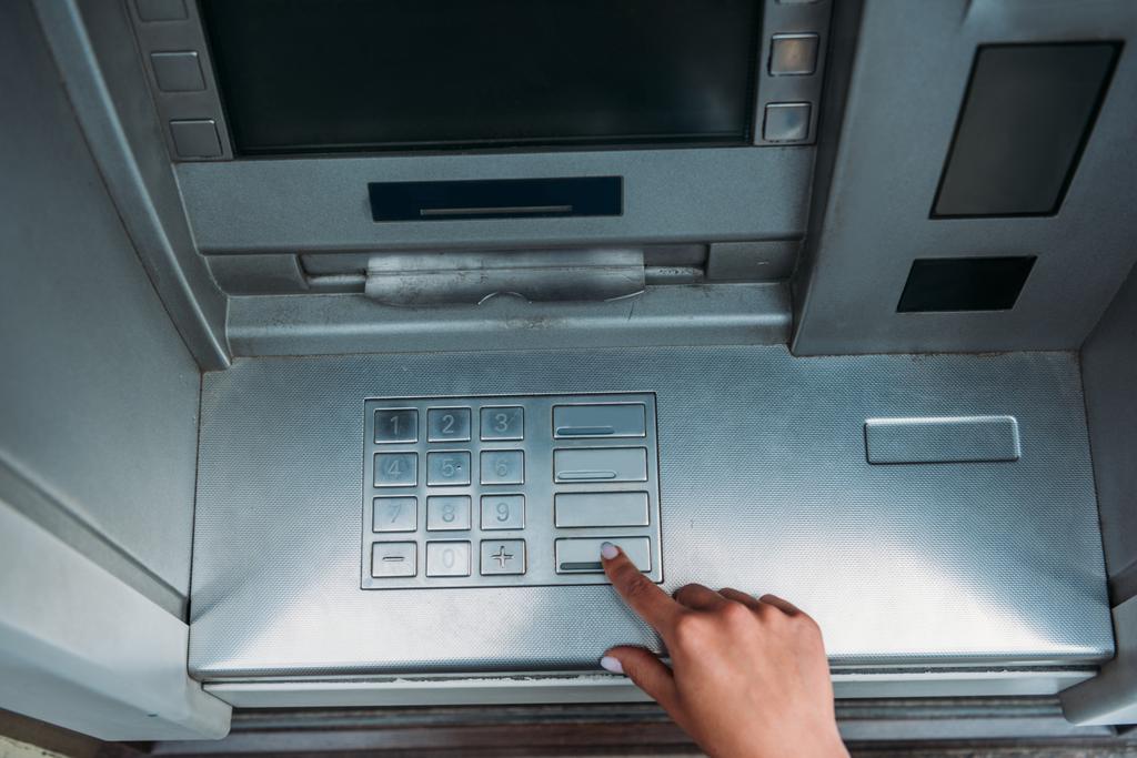 vista superior da mulher pressionando o botão na máquina ATM
  - Foto, Imagem