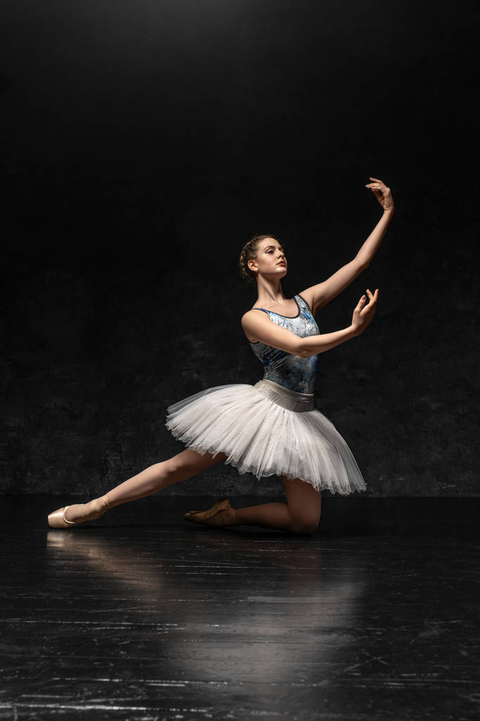 Baleriny. Młoda wdzięku baletnica ubrana w profesjonalny strój, Pointe buty z wstążkami i białym Tutu, pokazuje umiejętności taneczne. Piękny klasyczny balet. - Zdjęcie, obraz