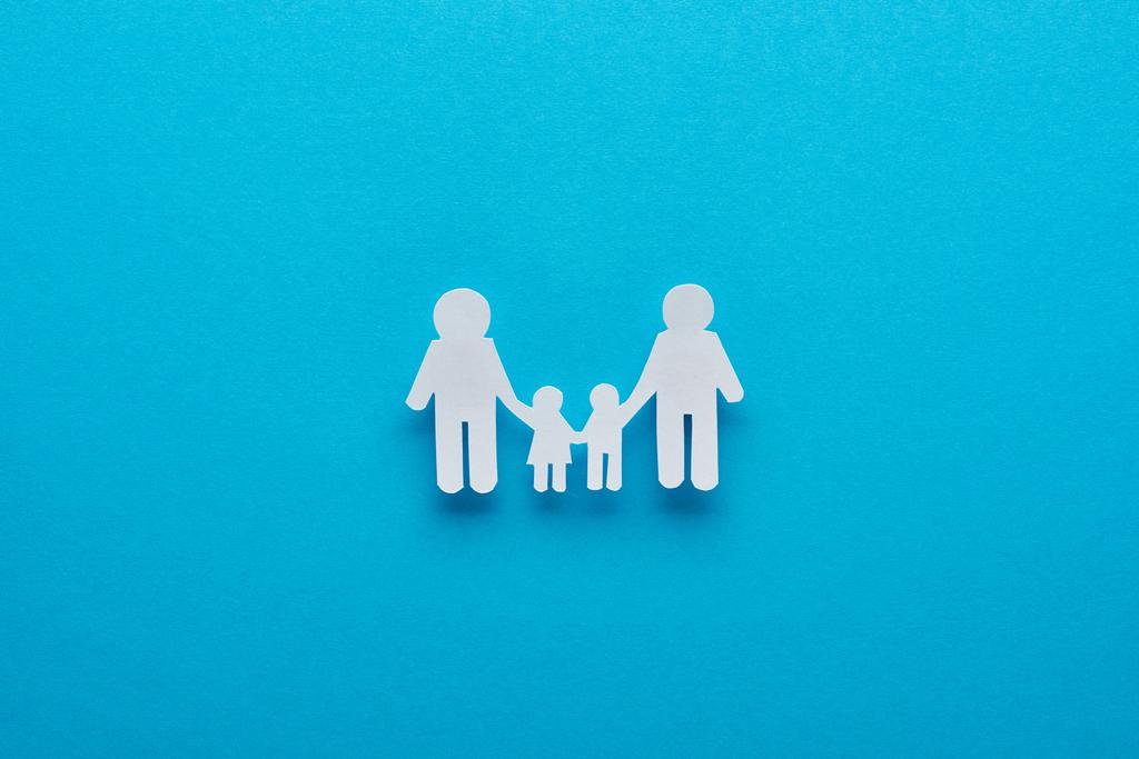 Top uitzicht van papier knippen familie Holding handen op blauwe achtergrond - Foto, afbeelding